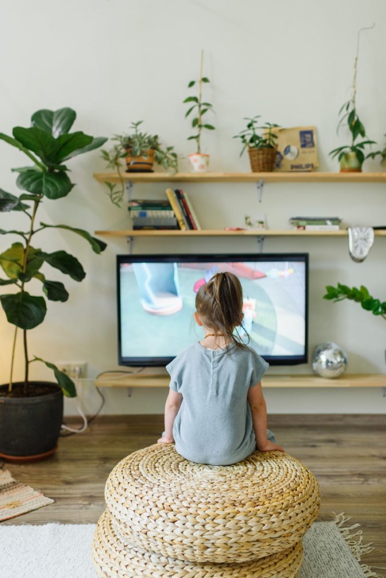 faceless girl watching tv on wicker stool at home